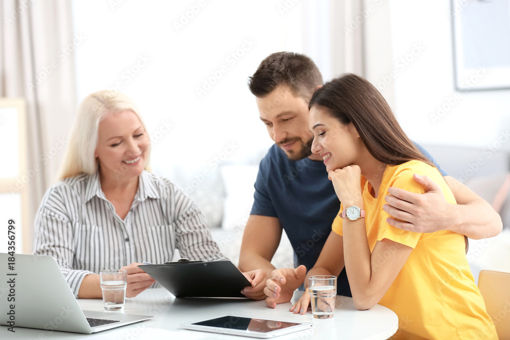 Female insurance agent consulting young couple in office