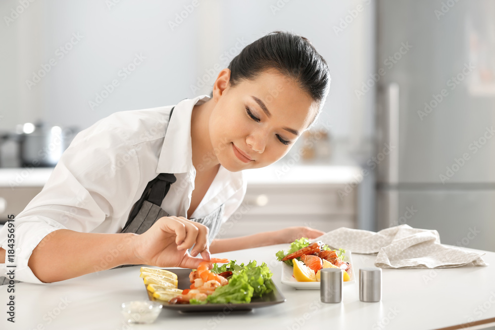 Beautiful Asian woman preparing dish with shrimps at table in kitchen Beautiful Asian woman preparing dish with shrimps at table in kitchen