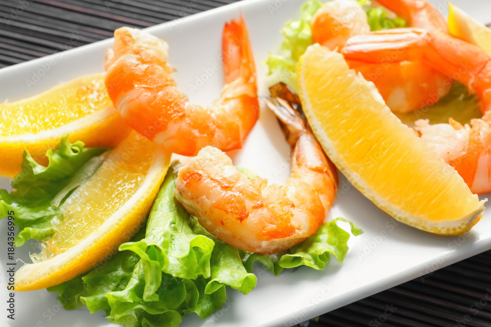 Delicious shrimps with lettuce and lemon on plate Delicious shrimps with lettuce and lemon on plate