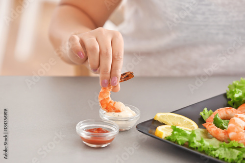 Young woman eating shrimp at table
