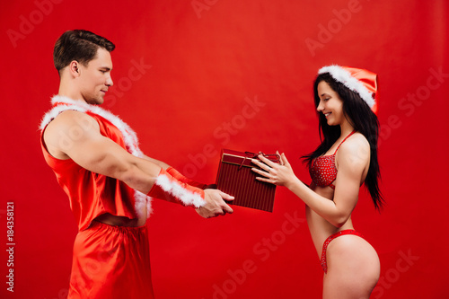 Christmas and New Year's gifts, holidays. sexy Santa Claus gives a gift box to hot girl