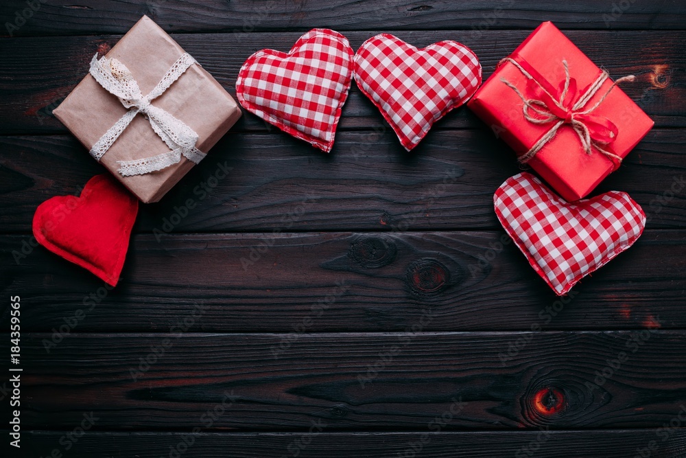 Obraz premium Valentines day background with handmaded hearts and gift boxes over dark wood, flat lay. Top view with copy space