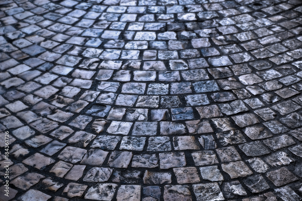 old cobblestone or cobble stone street road surface at night backlit background texture photo