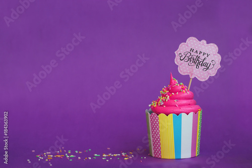 Canvas Print Tasty strawberry cupcake with sprinkles and Happy Birthday banner on violet background