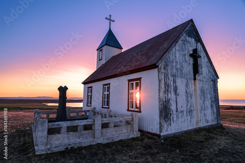 Sun shines through Saudaneskirkja Church at sunset on the Langanes Peninsula, Iceland