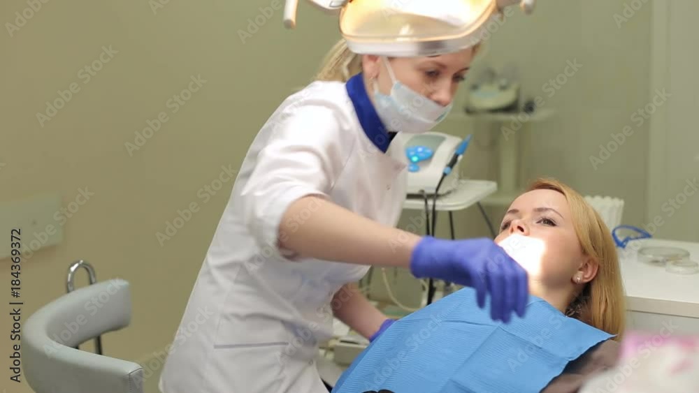 A young woman lies in an armchair in a dental clinic. Preparation for examination of the patient in the dental clinic. The dentist is preparing to examine the patient. A young woman lies in an armchair in a dental clinic. Preparation for examination of the patient in the dental clinic. The dentist is preparing to examine the patient.