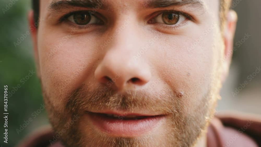 Close up of the handsome caucasian young man's face with a beard smiling to the camera. Portrait. Inside Close up of the handsome caucasian young man's face with a beard smiling to the camera. Portrait. Inside