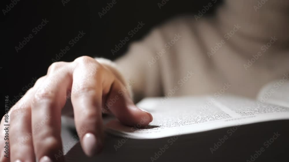 Student girl flips a page while reading a Bible book, Slow motion. Close up hands. Student girl flips a page while reading a Bible book, Slow motion. Close up hands.