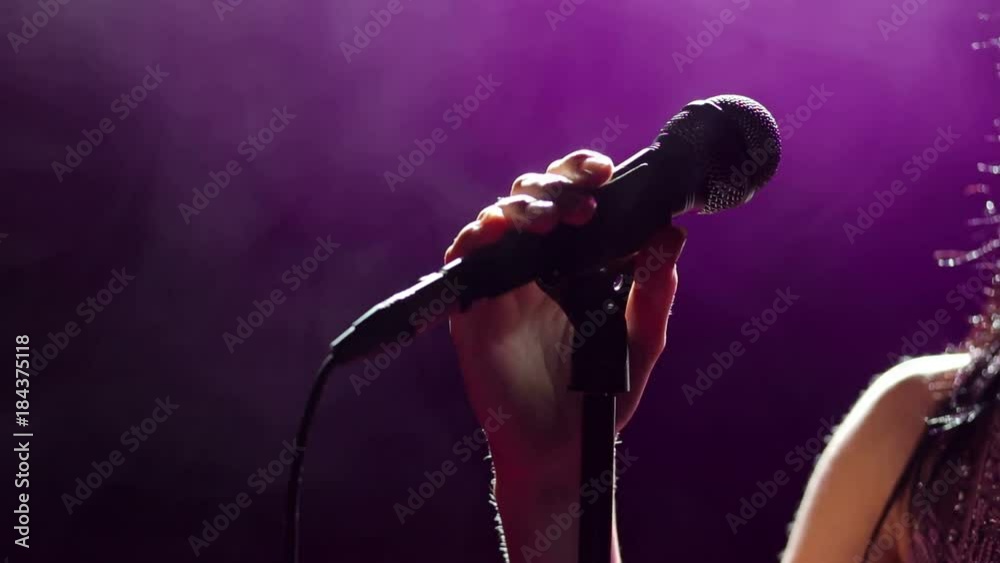 Hand Singer Microphone in hand singer on stage. Close-up. Silhouette of singer on ...