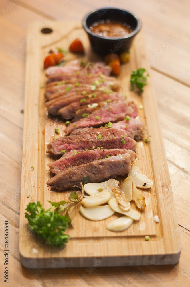 Top view of grilled beef tenderoid steak with spices sauce and garlic on cutting board Top view of grilled beef tenderoid steak with spices sauce and garlic on cutting board