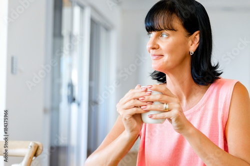 Happy woman with cup of tea or coffee at home