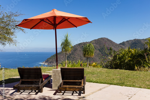 Sunbeds overlooking tropical rainforest and the bay of Puerto Vallarta, Mexico © Zstock