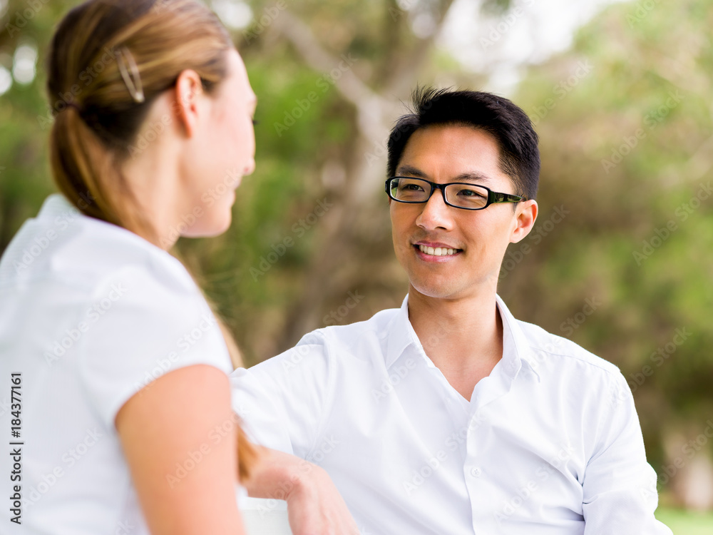 Portrait of smiling couple sitting in park and talking Portrait of smiling couple sitting in park and talking