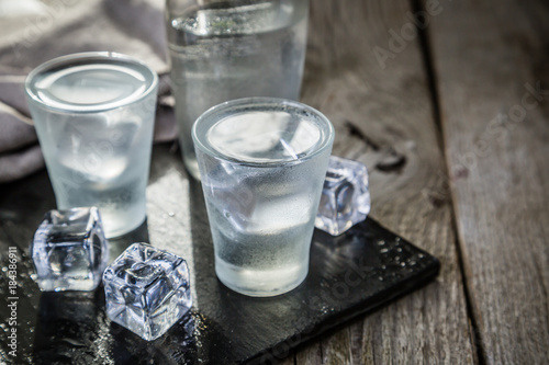 Vodka in shot glasses on rustic wood background
