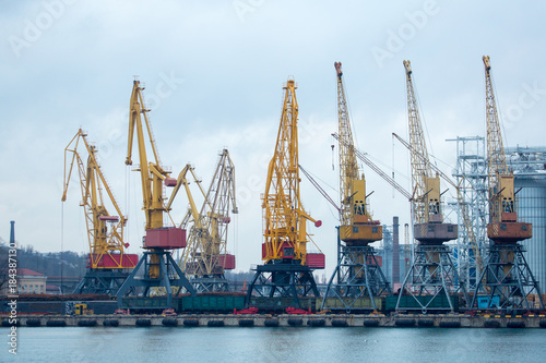 Railroad cars in port for loading unloading. Port cranes unload, load freight railroad cars in industrial port at port terminal