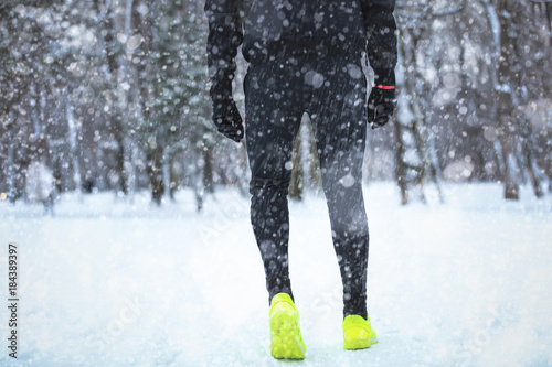Man exercising and running in the park filled with snow.