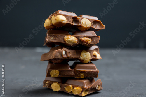Pile of dark chocolate with nuts on the wooden table. Selective focus. Shallow depth of field.