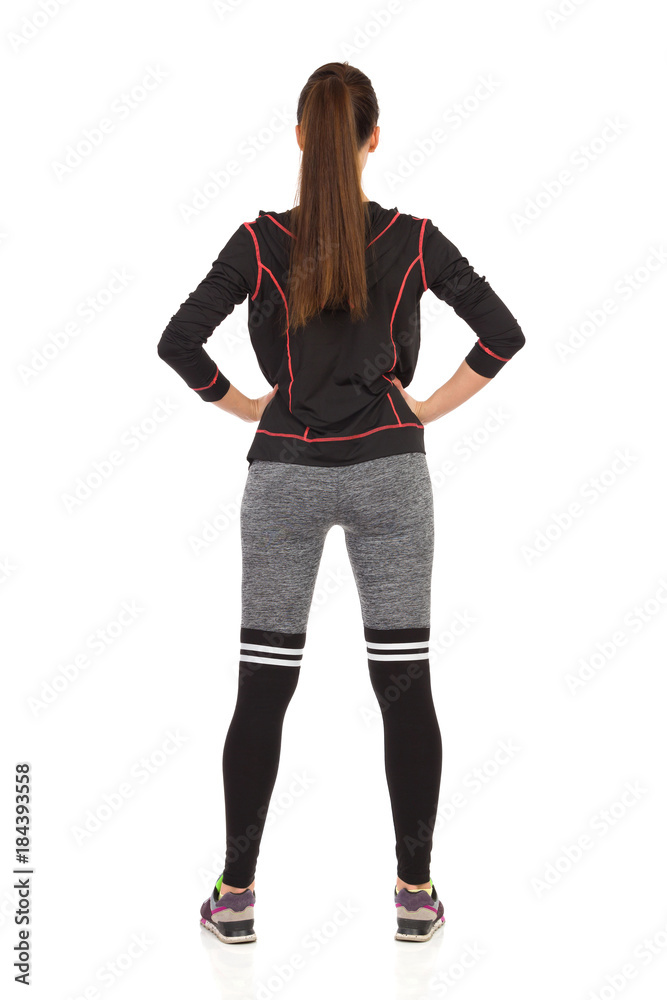 Fototapeta premium Woman Standing Legs Apart In Fitness Outfit. Rear View.