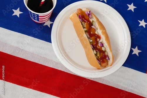 Hot dog served in plate with a drink on American flag