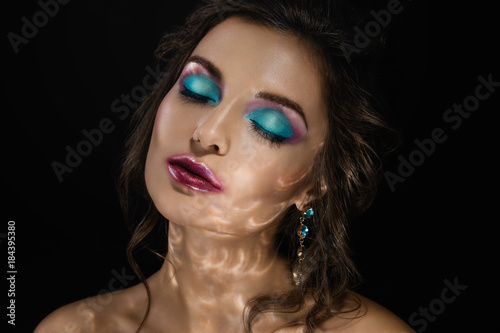 Woman in darkness with a light reflection on her face