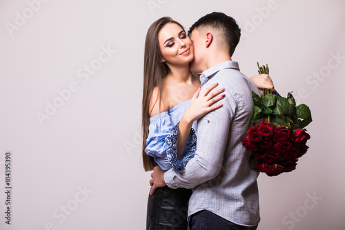 Young couple with roses kissing isolated on white photo