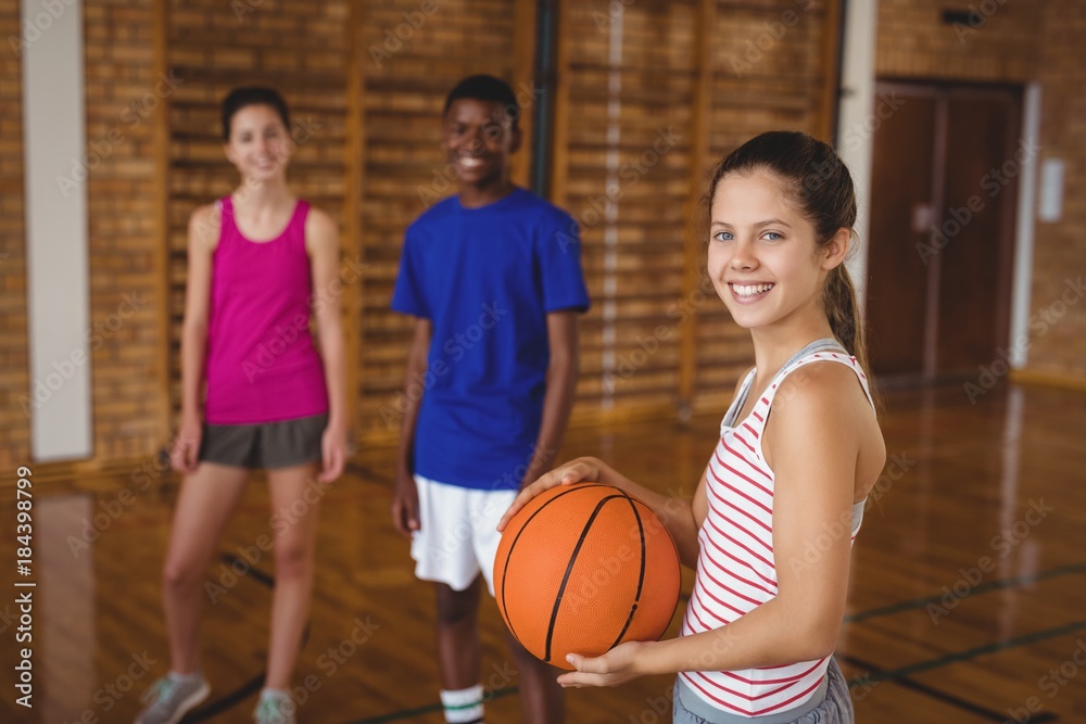 Portrait of smiling high school kids standing with basketball