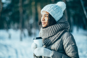 Pensive African woman walking over winter forest