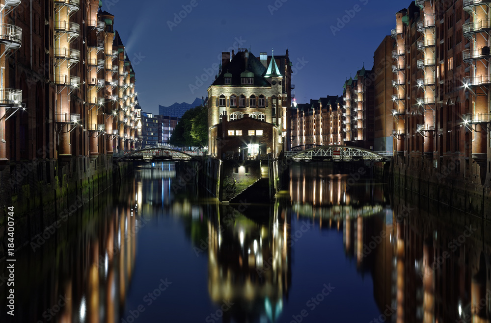 Obraz premium Hamburg Zollkanal mit historischer Speicherstadt im Hintergrund bei Nacht