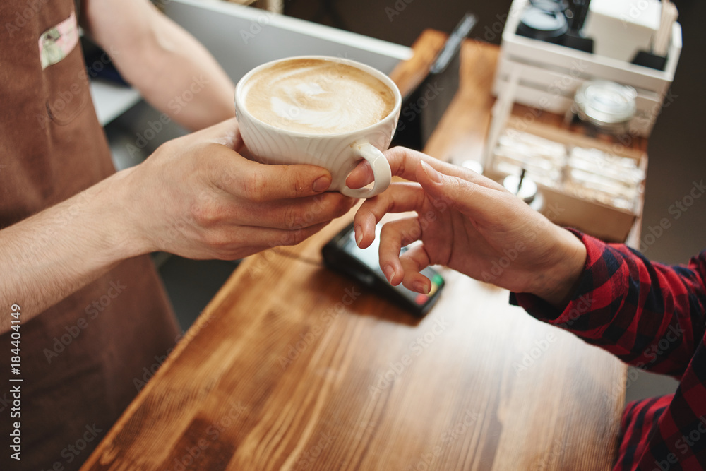 The girl picks up a coffee from a Barista. Hands and Cup closeup