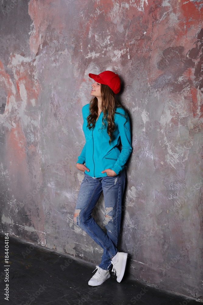 Resting young woman standing near loft wall background, stylish street lifestyle