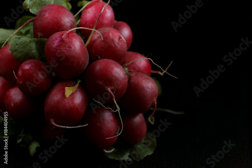 radish ripe with green leaves on black background