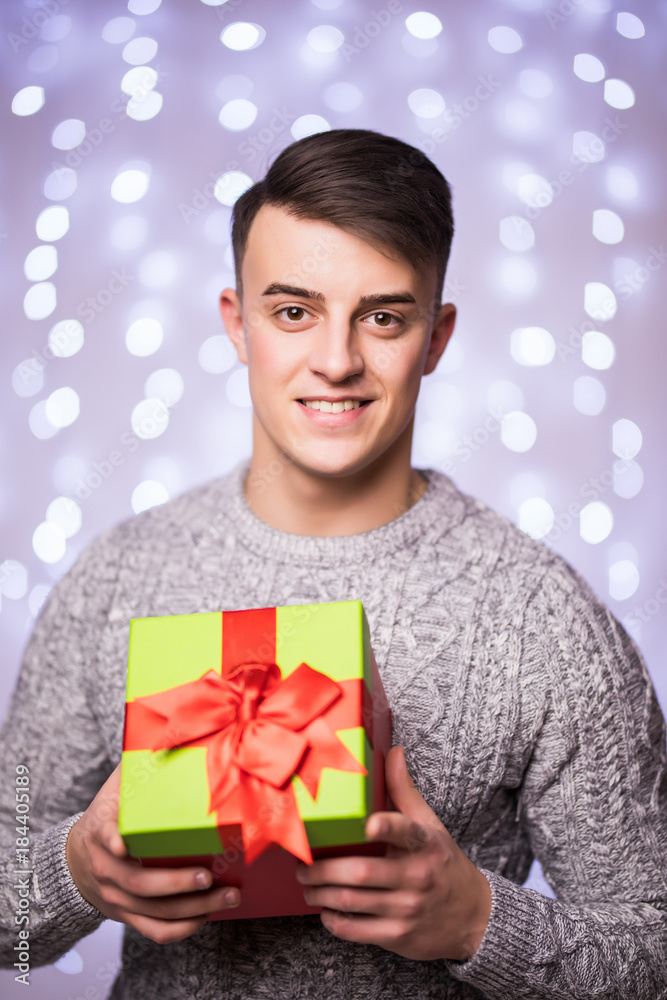 Portrait of Smiling man with Christmas gift on bokeh background. Man with gift on blur background Portrait of Smiling man with Christmas gift on bokeh background. Man with gift on blur background
