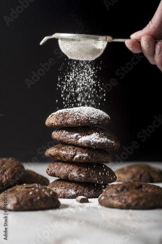 фотографія Dark chocolate chip cookies on a pile, sifting powdered sugar on the top