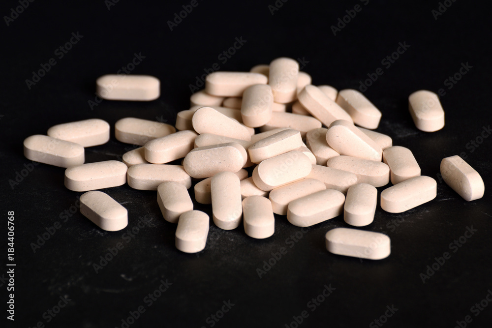 White, long-lasting white tablets are scattered on a black background White, long-lasting white tablets are scattered on a black background