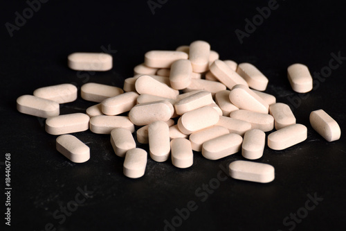  White, long-lasting white tablets are scattered on a black background