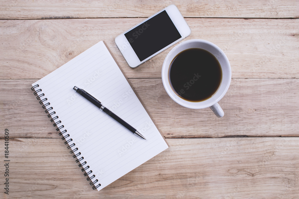Top view Note book with pen and smartphone and a cup of coffee on wood table for Business Top view Note book with pen and smartphone and a cup of coffee on wood table for Business