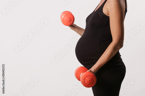 Pregnant woman training with dumbbells