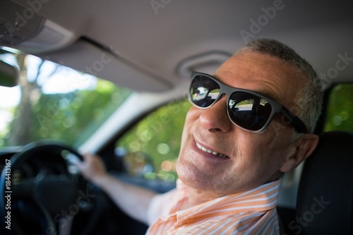 Portrait of smiling senior man wearing sunglasses in car