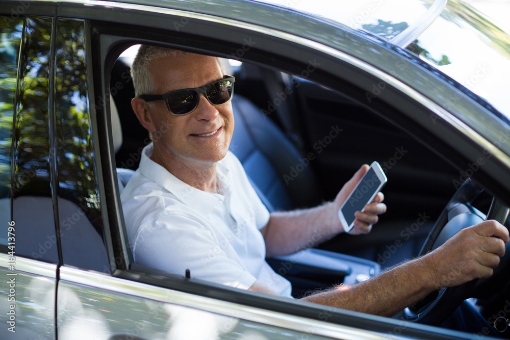 Portrait of senior man using mobile phone in car