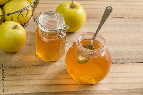 Apple jelly jam in glass jar on wooden table with apples - selective focus