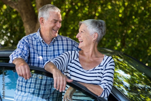 Senior couple leaning on car door