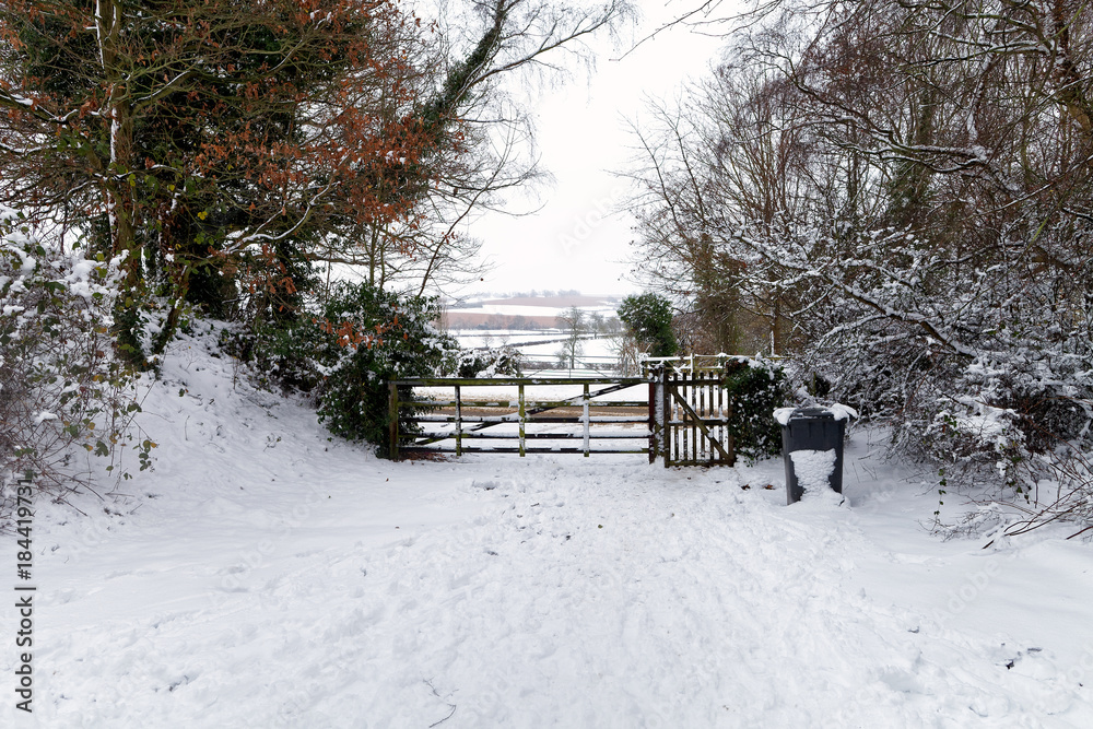 Snow covered wooden gate with winter countryside in the background