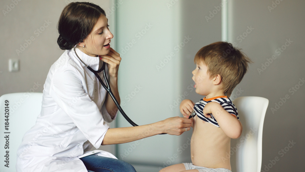 Φωτογραφία Young woman doctor listening little boy with stethoscope in medical office