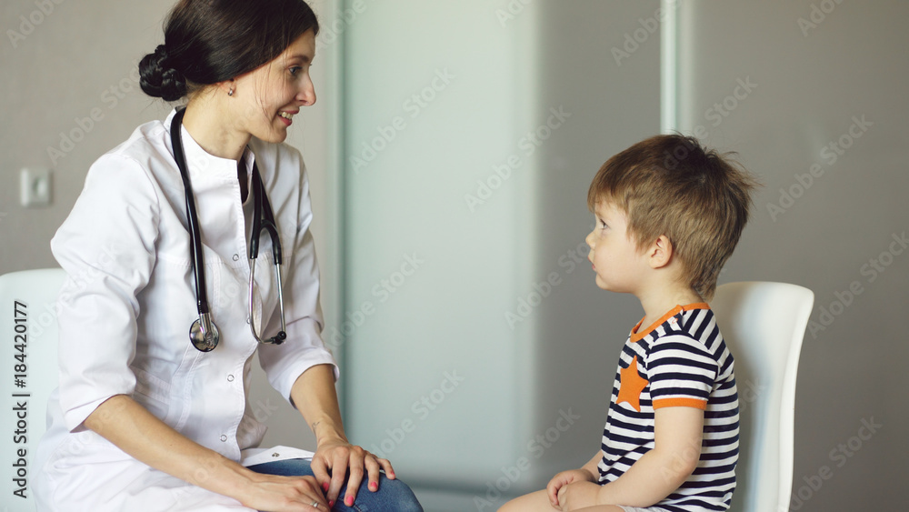 Φωτογραφία Young woman doctor talking little boy and listening with stethoscope in medical