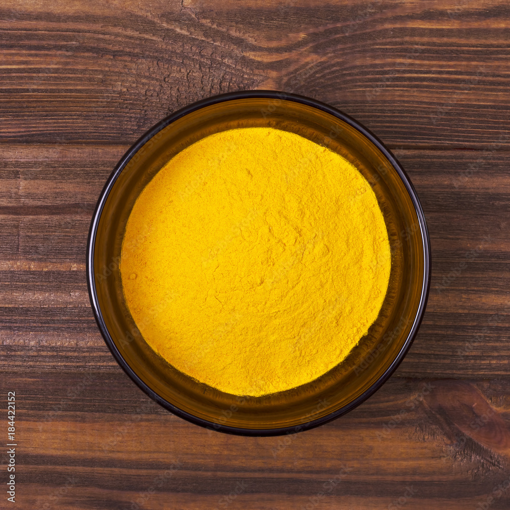 Turmeric powder in a bowl on a wooden background Turmeric powder in a bowl on a wooden background
