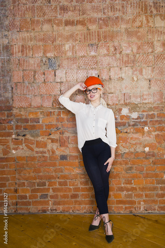 Portrait of architect student or painter with blueprints protect helmet wearing. Brick red background.