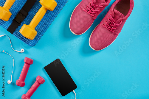 Bilde på lerret Sport shoes, dumbbells and mobile phone on blue background
