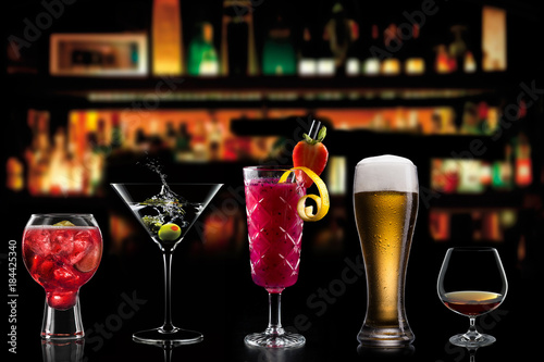 Selection of cocktails martini spritz bramble gin tonic beer bramble bar blurred black background