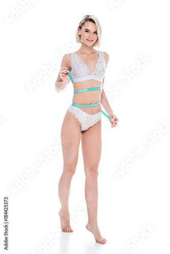 smiling girl in lingerie measuring her perfect slim body, isolated on white