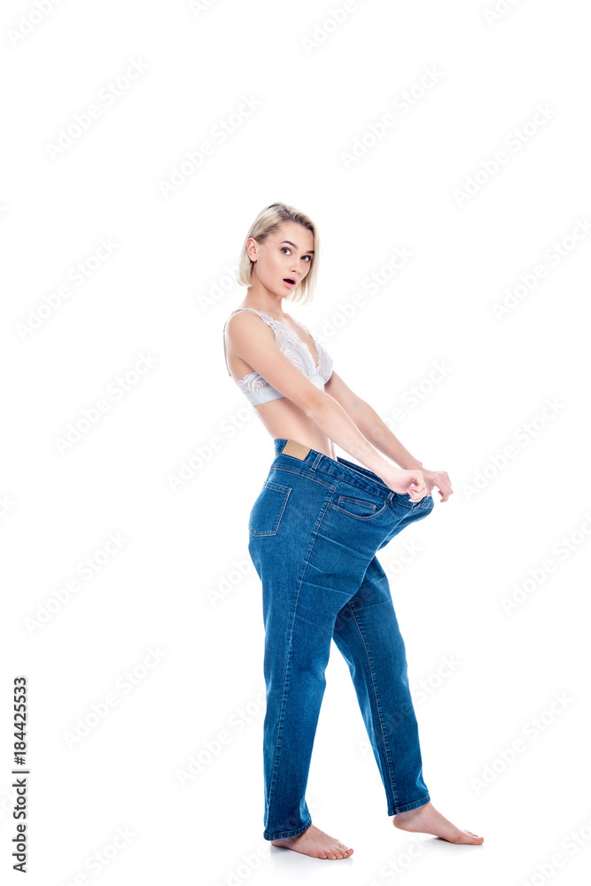 shocked girl showing weight loss by wearing old jeans, isolated on white shocked girl showing weight loss by wearing old jeans, isolated on white